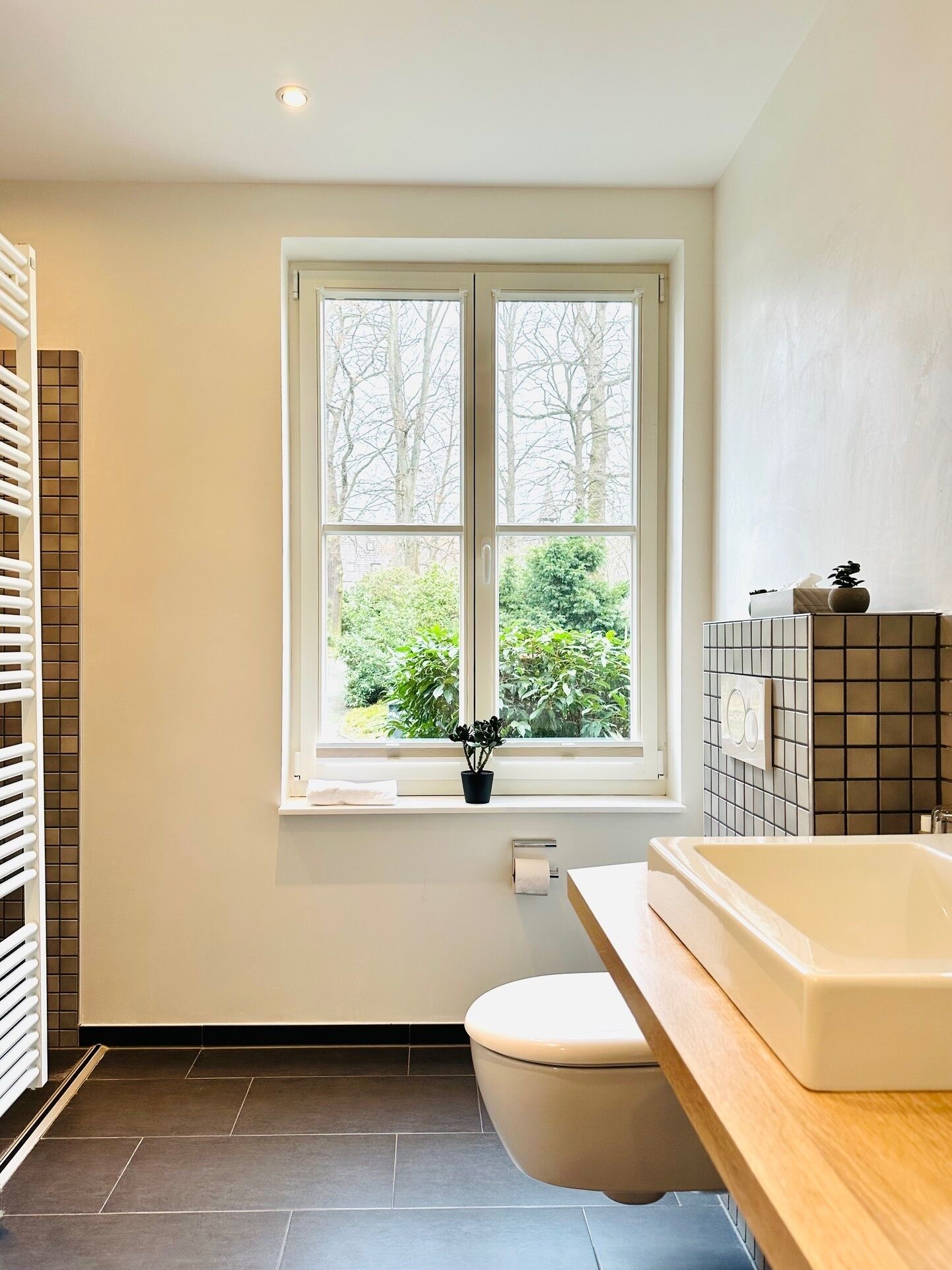 Ein modernes Badezimmer mit großem Fenster, einer Badewanne und einer Toilette.