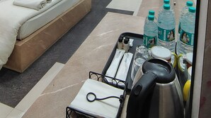 Habitación de hotel con una cama, una silla roja, un escritorio, un ventilador de techo y un minibar.