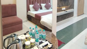 A hotel room with a bed, a sitting area, a mirror, a TV, and a tray with toiletries.