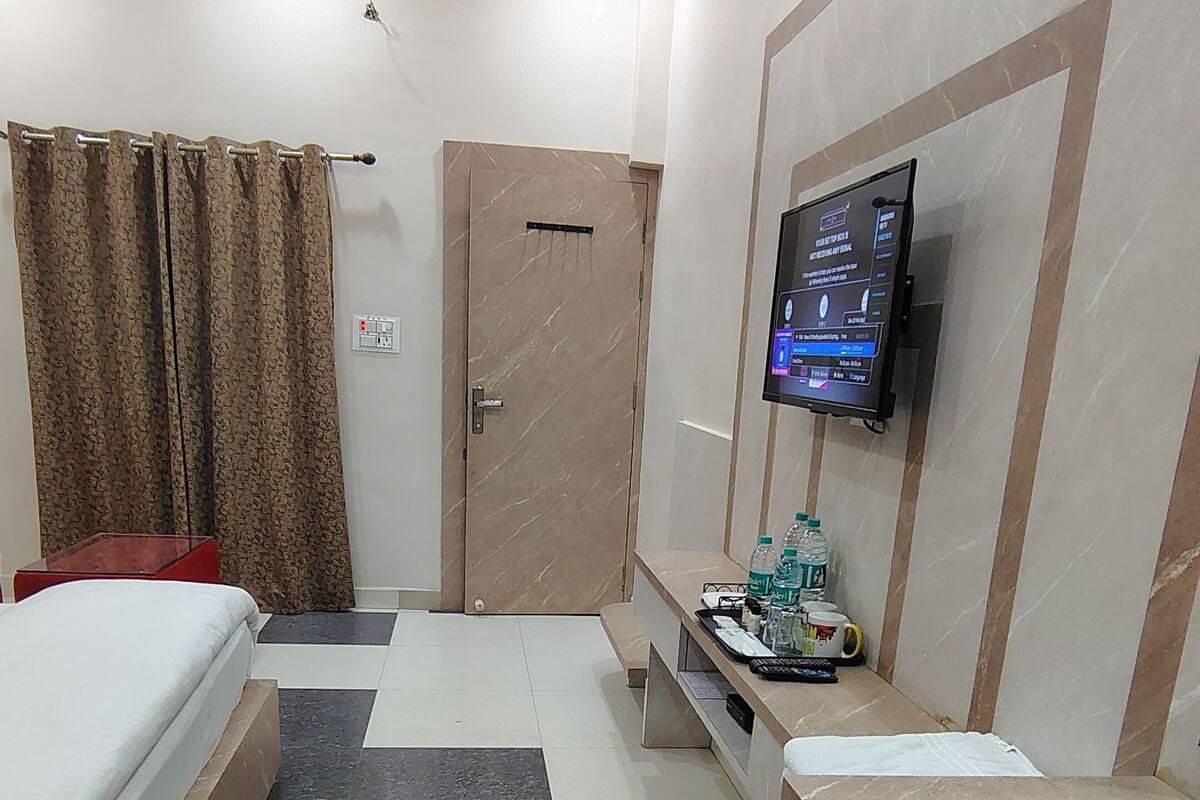Habitació d'hotel moderna amb un llit, una taula de treball amb un ordinador, una televisió i una zona de bany.