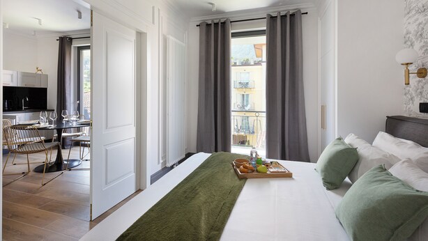 Ein Hotelzimmer mit Bett, Frühstückswagen, Essbereich und Blick ins Freie.