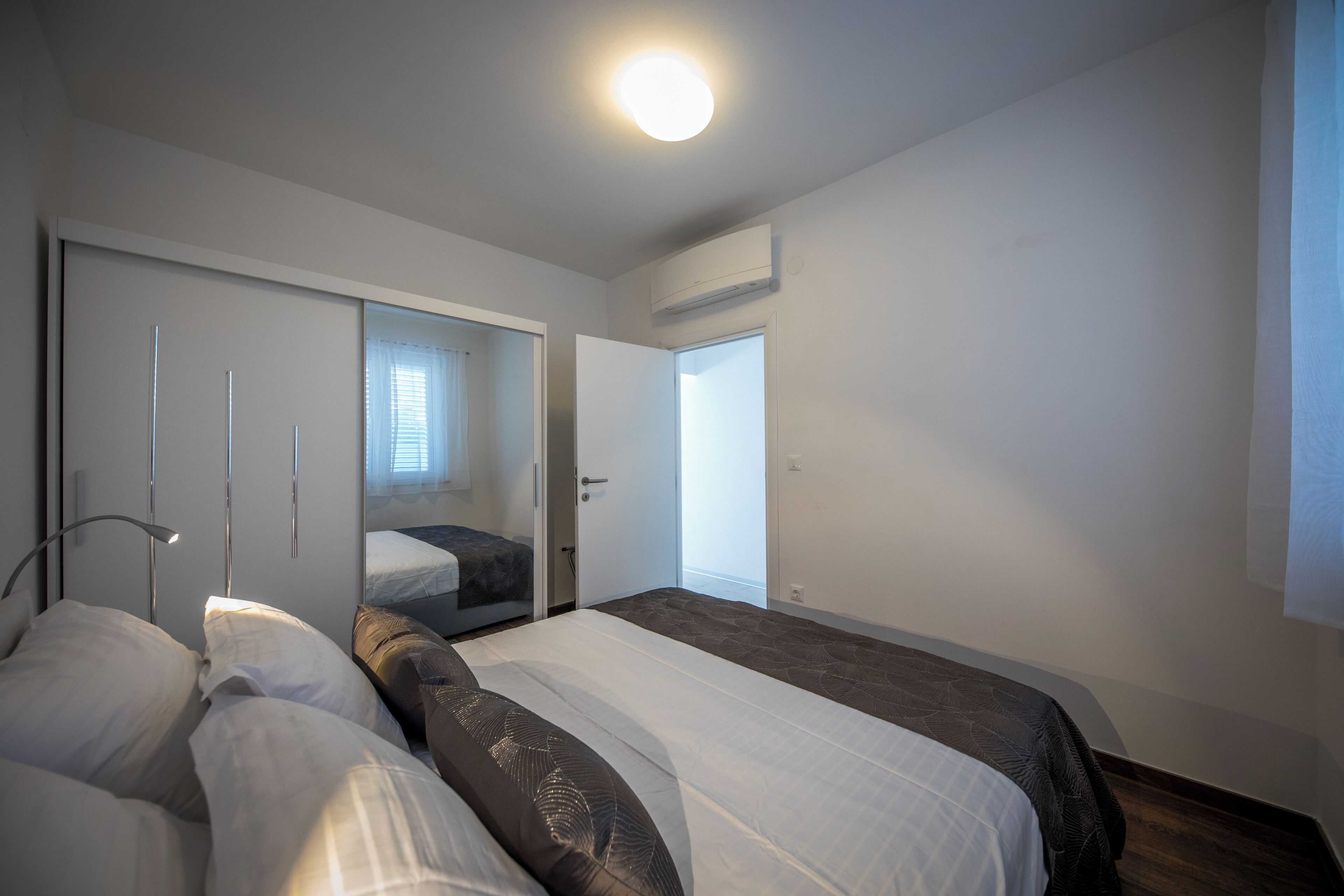 Un dormitorio moderno con una cama grande, una mesita de noche, un espejo y un armario.