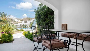 Une terrasse avec une table et des chaises, une vue sur une piscine et une montagne en arrière-plan.