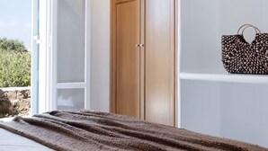A bedroom with a bed, a wooden wardrobe, and a handbag on the wall. - Mykonos pool house 5 shared pool - My rental Homes (Mykonos)