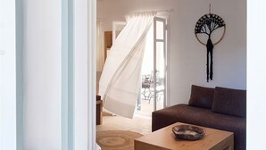 An interior with a wooden table, a brown sofa, and a wall-mounted decor piece. - Mykonos pool house 5 shared pool - My rental Homes (Mykonos)