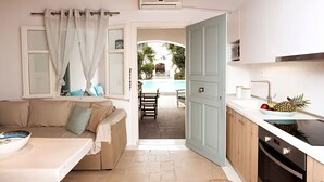 Una habitación acogedora con un sofá color crema, una mesa de comedor y una cocina con estufa y fregadero.