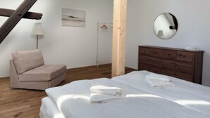 Makuuhuone, jossa on sänky, puinen lipasto, vaateteline ja lamppu.