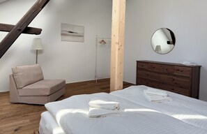 Ein Schlafzimmer mit einem Bett, einem Holzschrank, einem Kleiderständer und einer Lampe.
