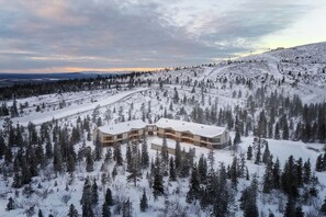 A modern, multi-story building surrounded by a snowy forest. - Stay North - Utsuvaara Gielas (Kittilä)