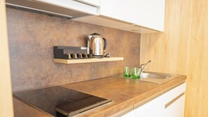 Una cocina moderna con estufa integrada, hervidor y un recipiente de vidrio sobre la encimera.