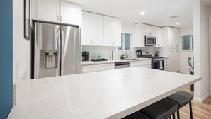 A modern kitchen with white cabinets, stainless steel appliances, and a central island.