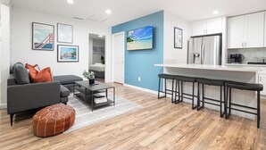 A modern living room with a grey sofa, a coffee table, and a wooden floor.