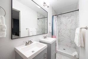 Een moderne badkamer met twee wastafels, een grote spiegel en een douchehoek.