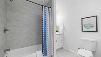Une salle de bain avec douche, toilettes et lavabo.