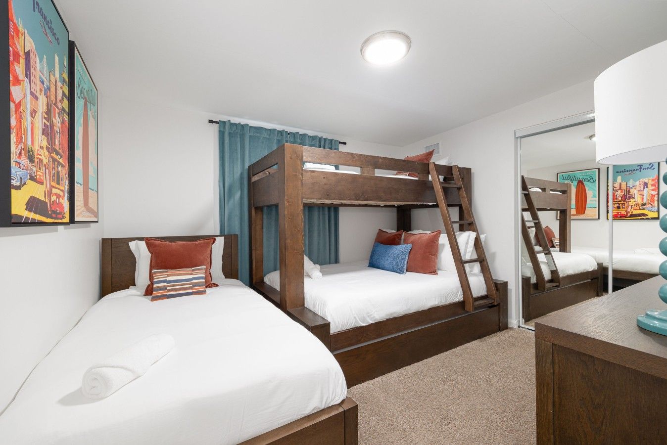 A bunk bed room with a ladder, a desk, and a mirror.