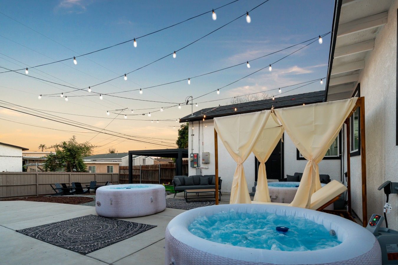Une terrasse extérieure dotée d’un jacuzzi, d’un espace salon et de guirlandes lumineuses.