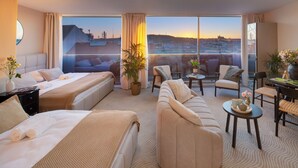 Ein Hotelzimmer mit einem großen Bett, einer Couch, einem Essbereich und einem Balkon mit Blick auf die Stadt.