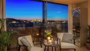 Ein Balkon mit zwei Stühlen, einem Tisch mit Teekanne und Tassen sowie einer Vase mit Blumen.