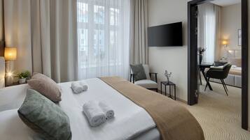 Habitación de hotel con cama, escritorio, silla, televisor y vista a la ciudad por la ventana.