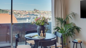 Ein Balkon mit Tisch, Stühlen, einer Blumenvase, einer Pflanze und einem Buch.
