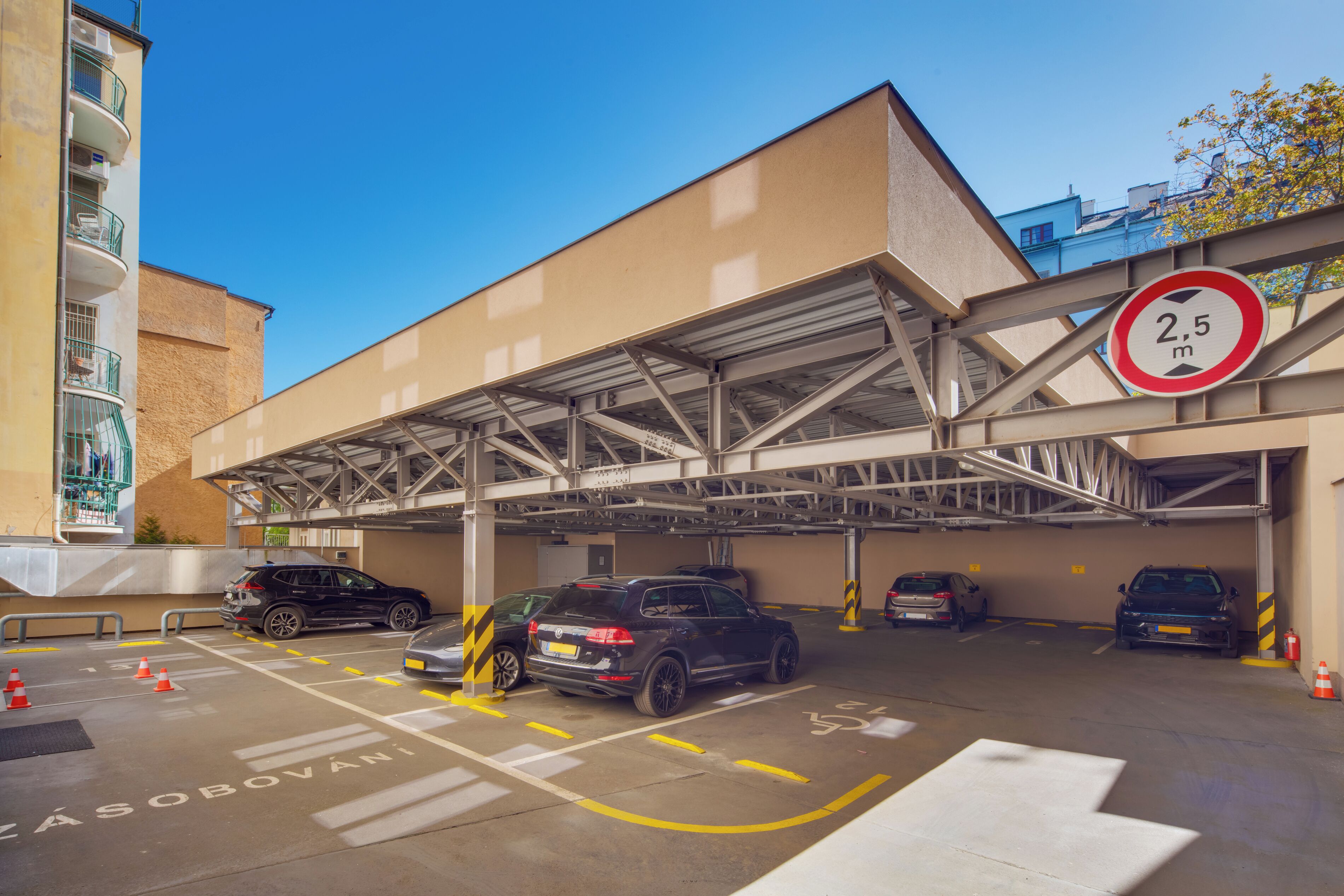 A multi-level parking garage with cars parked in designated spaces, a clear blue sky, and a height restriction sign.