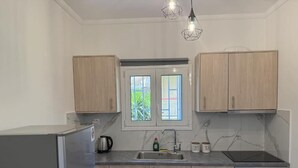 Eine moderne Küche mit hellen Holzschränken, einem Edelstahlkühlschrank, einem Einbauofen und einem Fenster mit Blick auf Grünflächen.