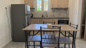 Eine kleine Küche mit Holzausbau, einem integrierten Kühlschrank, einem Esstisch mit Stühlen und einem Fenster über der Spüle.