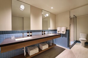 A bathroom with a double sink, a large mirror, a glass shower enclosure, and a toilet.