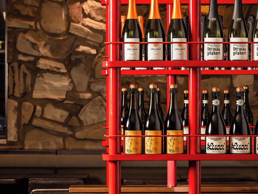 A wine rack with bottles, a stone wall, and wooden seating.