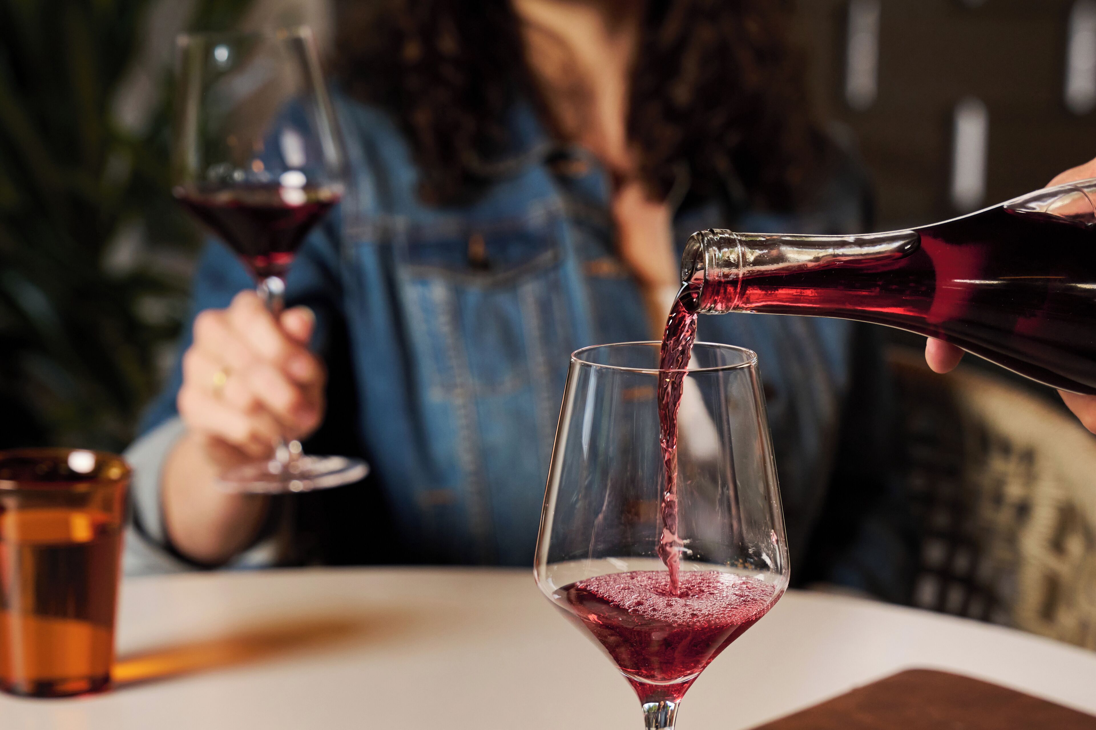 Une personne verse un liquide rouge dans un verre.