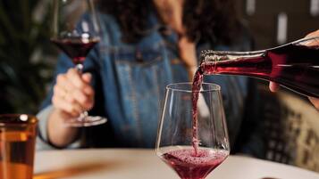 Une personne verse un liquide rouge dans un verre.