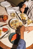 Una mesa de comedor con platos de comida, copas de vino y cubiertos.