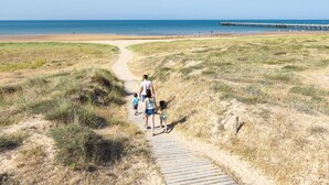 A sandy path leading to a beach with a pier in the distance. - Comfortable house for 8 with garden (Saint-Gilles-Croix-de-Vie)