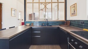 A modern kitchen with a large window, dark cabinetry, and a built-in stove. - Comfortable house for 8 with garden (Saint-Gilles-Croix-de-Vie)
