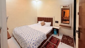Een slaapkamer met een bed, een plafondventilator, een nachtkastje, een spiegel en een deur.