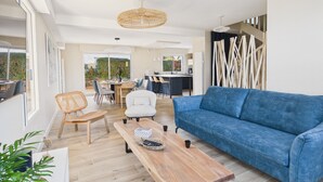 A modern living room with a blue sofa, wooden coffee table, and wicker chairs. - 100m from the beach – House for 8 with garden (Fouesnant)