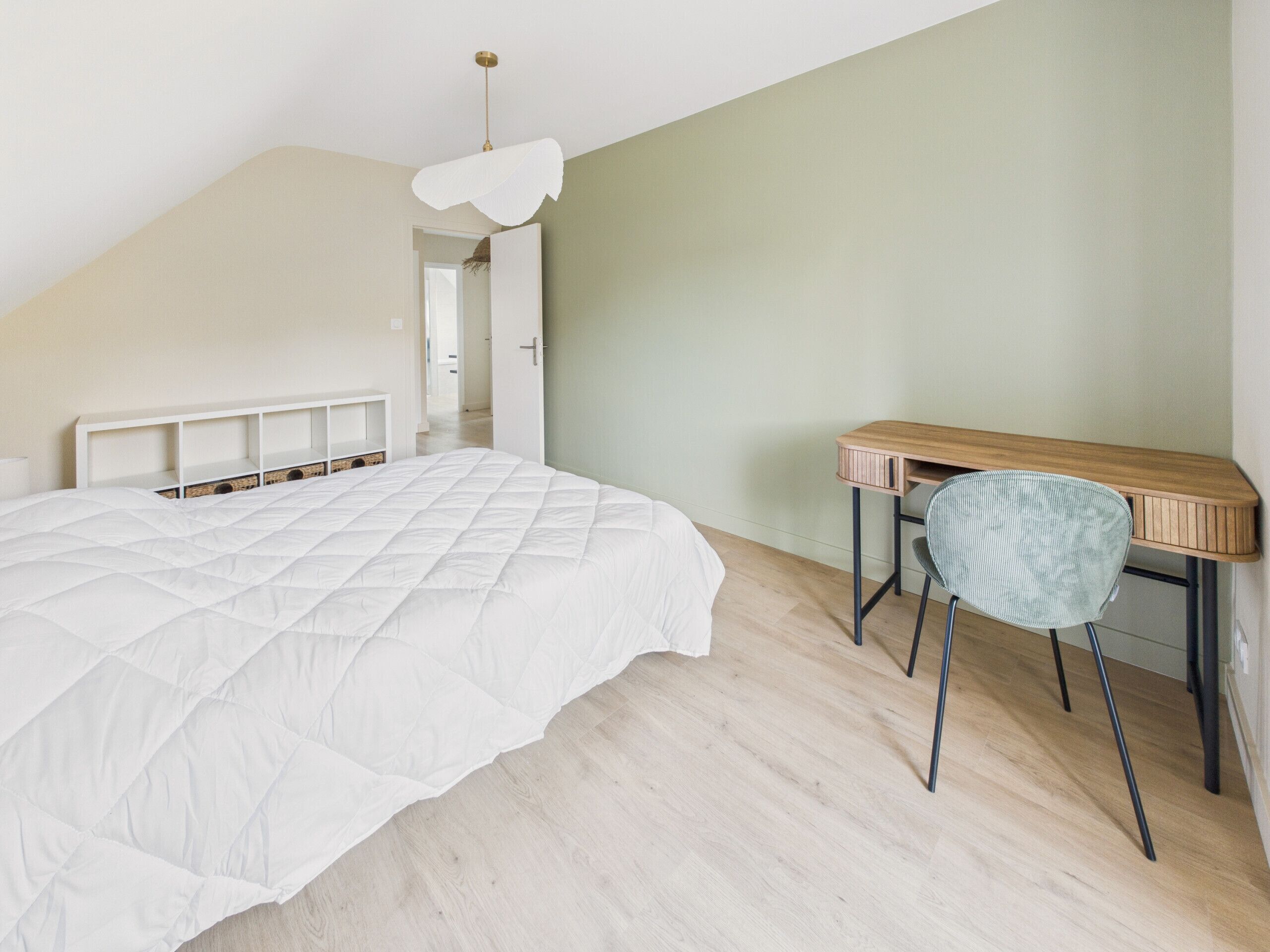 A bedroom with a bed, a desk, and a chair.