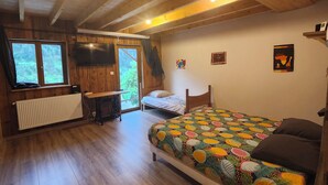Une chambre dans une cabane en bois, avec un lit, un bureau, un radiateur et une fenêtre.