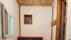 Une pièce avec un plafond en bois, une porte coulissante, une petite fenêtre et un escalier en bois.