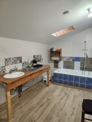 A bathroom with a wooden vanity, a sink, a bathtub, and a shower.
