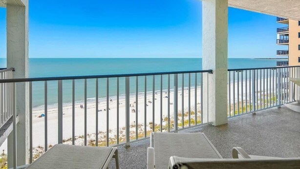 A balcony with a view of a beach and ocean. - Beachfront 3BR, 2BA Apollo condo with pool, WiFi, and heated Gulf views. (Marco Island)