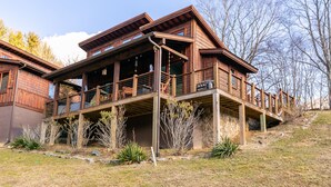 A wooden multi-level house with a balcony, surrounded by a landscaped garden. - Ripple Run at Eagles Nest - pets allowed, hot tub, grill, community amenities, Fish Camp section (Banner Elk)