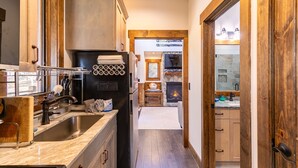 A kitchen with a large sink, wooden cabinets, and a stone fireplace. - Ripple Run at Eagles Nest - pets allowed, hot tub, grill, community amenities, Fish Camp section (Banner Elk)