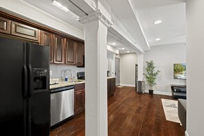 Une cuisine moderne dotée d’appareils électroménagers en acier inoxydable, de meubles en bois et d’un grand réfrigérateur.
