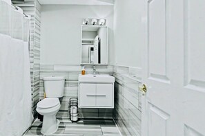 Un baño con inodoro, lavamanos, espejo y toallero.