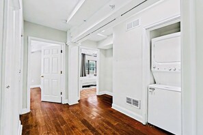 A hallway with wooden flooring, white walls, and a laundry area with a dryer and washing machine. - Prime 3BR Philly Pad Fits 6 Guests Walk Everywhere (Philadelphia)