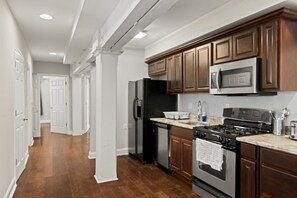 A kitchen with wooden cabinets, stainless steel appliances, and a marble countertop. - Stylish 3BR Sleeps 6 Oasis | Near The Liberty Bell (Philadelphia)