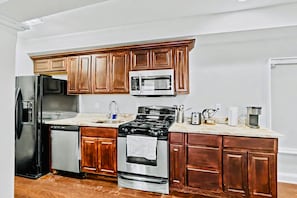 A kitchen with wooden cabinets, stainless steel appliances, and a marble countertop. - Prime 3BR Philly Pad Fits 6 Guests Walk Everywhere (Philadelphia)