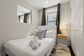 Une chambre d’hôtel comprenant un lit, une table de chevet avec une lampe, un miroir et une armoire.