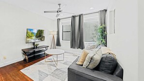 Een moderne woonkamer met een flatscreen televisie, een bank, een salontafel en een vloerlamp.